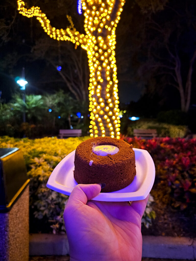 a mini pumpkin lava cake on a plate angled in front of a tree covered in lights