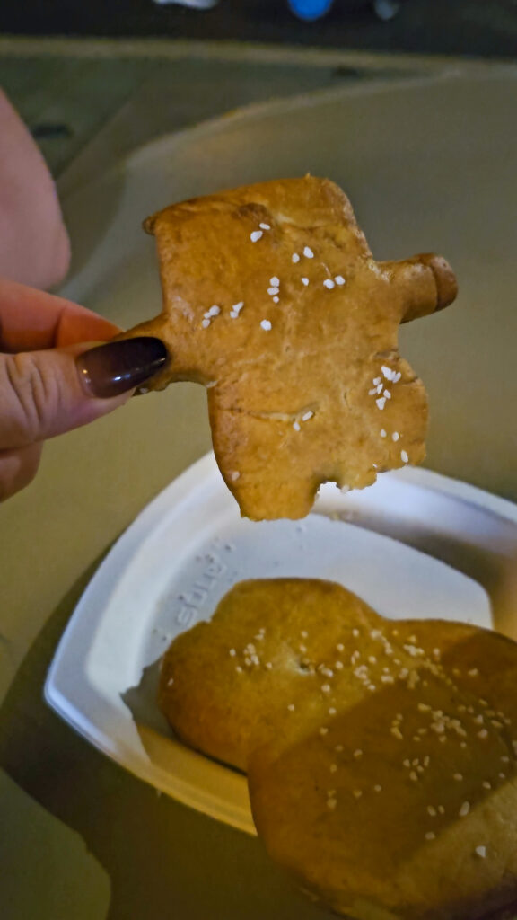 A hand holding the head broken off of a snowman shaped pretzel