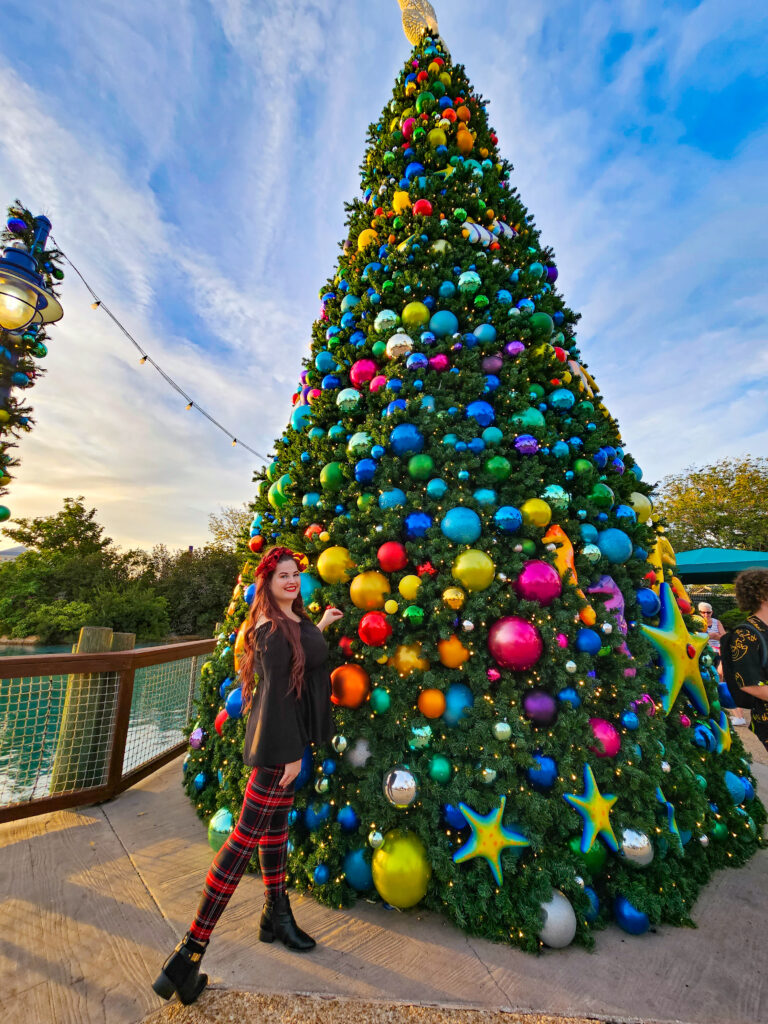 kristin standing in front of a large decorated christmas tree in seaworld orlando